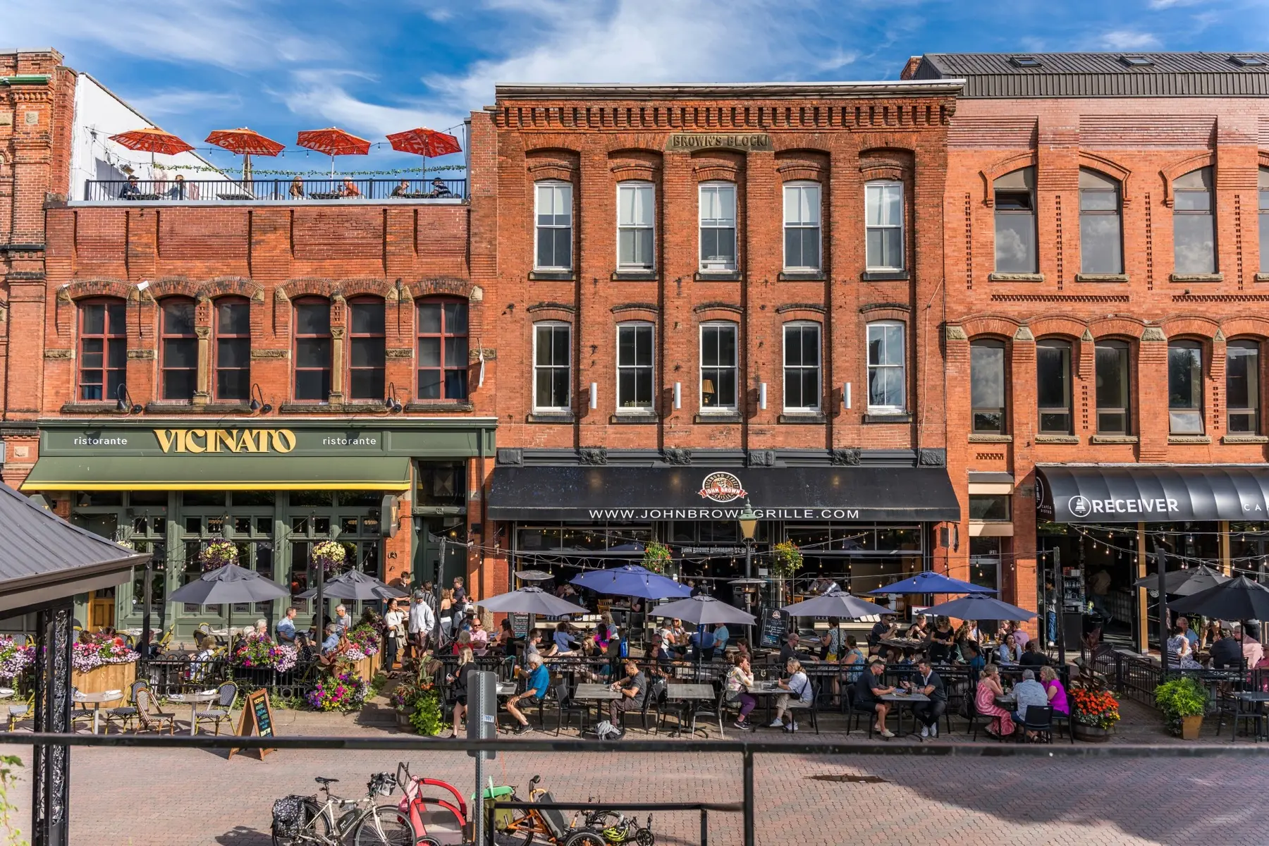 Patios under umbrellas on Victoria Row in Charlottetown, in late-day sun.
